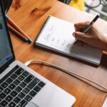 How to Write Blog Posts Faster Using AI Without Losing Your Voice 7 Isometric illustration of a laptop, notebook and checklist representing writing blog posts with AI assistance